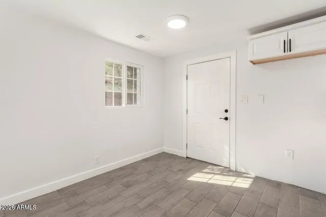 a view of an empty room with wooden floor and a window