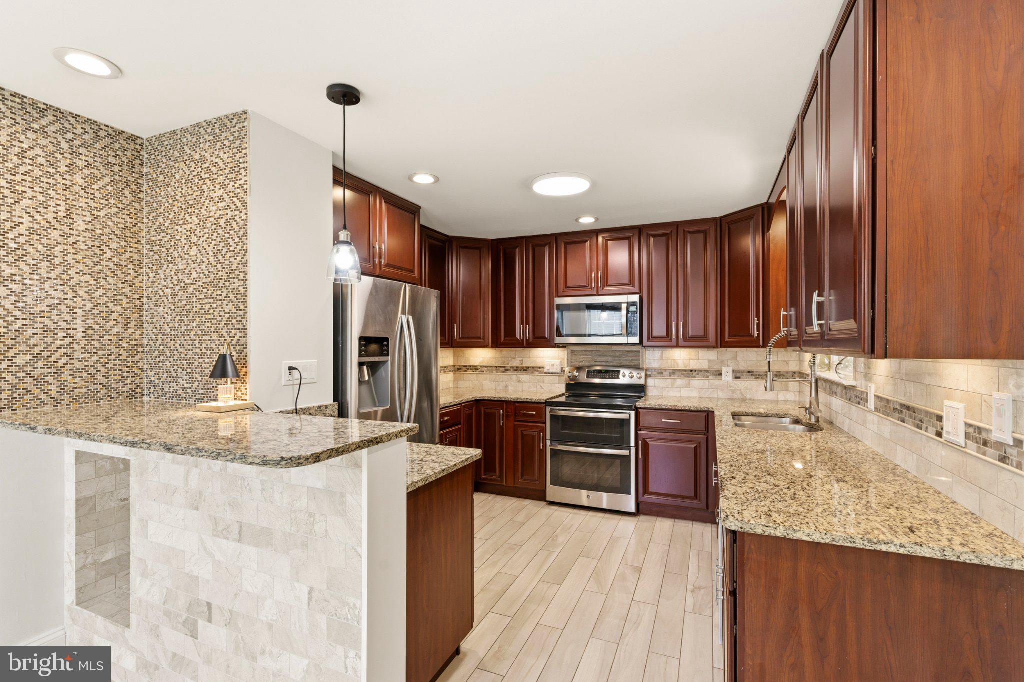 7845 Metacomet Road Hanover, MD 21076 - Photo 8 of 19 a kitchen with stainless steel appliances granite countertop a sink stove refrigerator granite counter tops and wooden cabinets