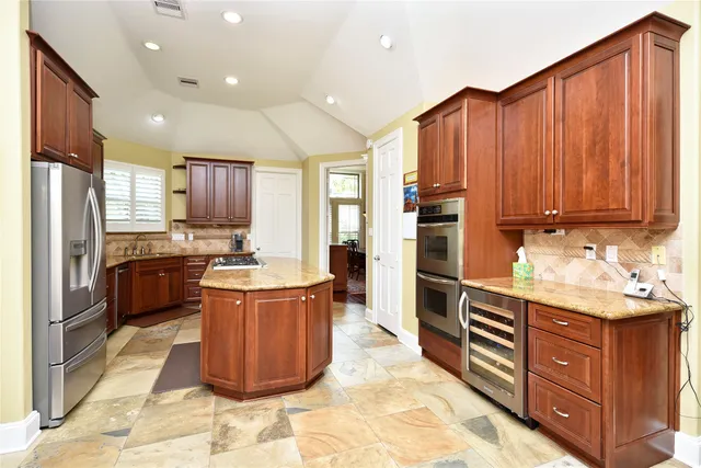 a kitchen with stainless steel appliances granite countertop a stove refrigerator and a sink