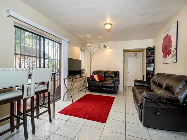 a living room with furniture a flat screen tv and a refrigerator