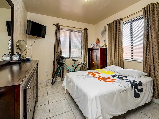 a bedroom with a bed a flat screen tv and windows