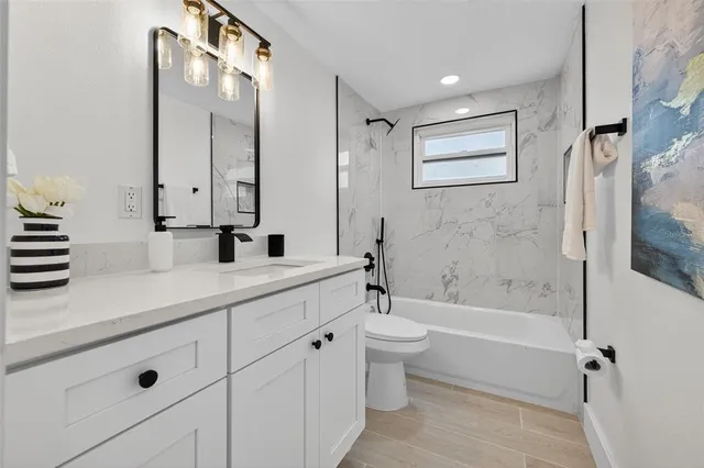 a bathroom with a bathtub shower sink vanity and toilet