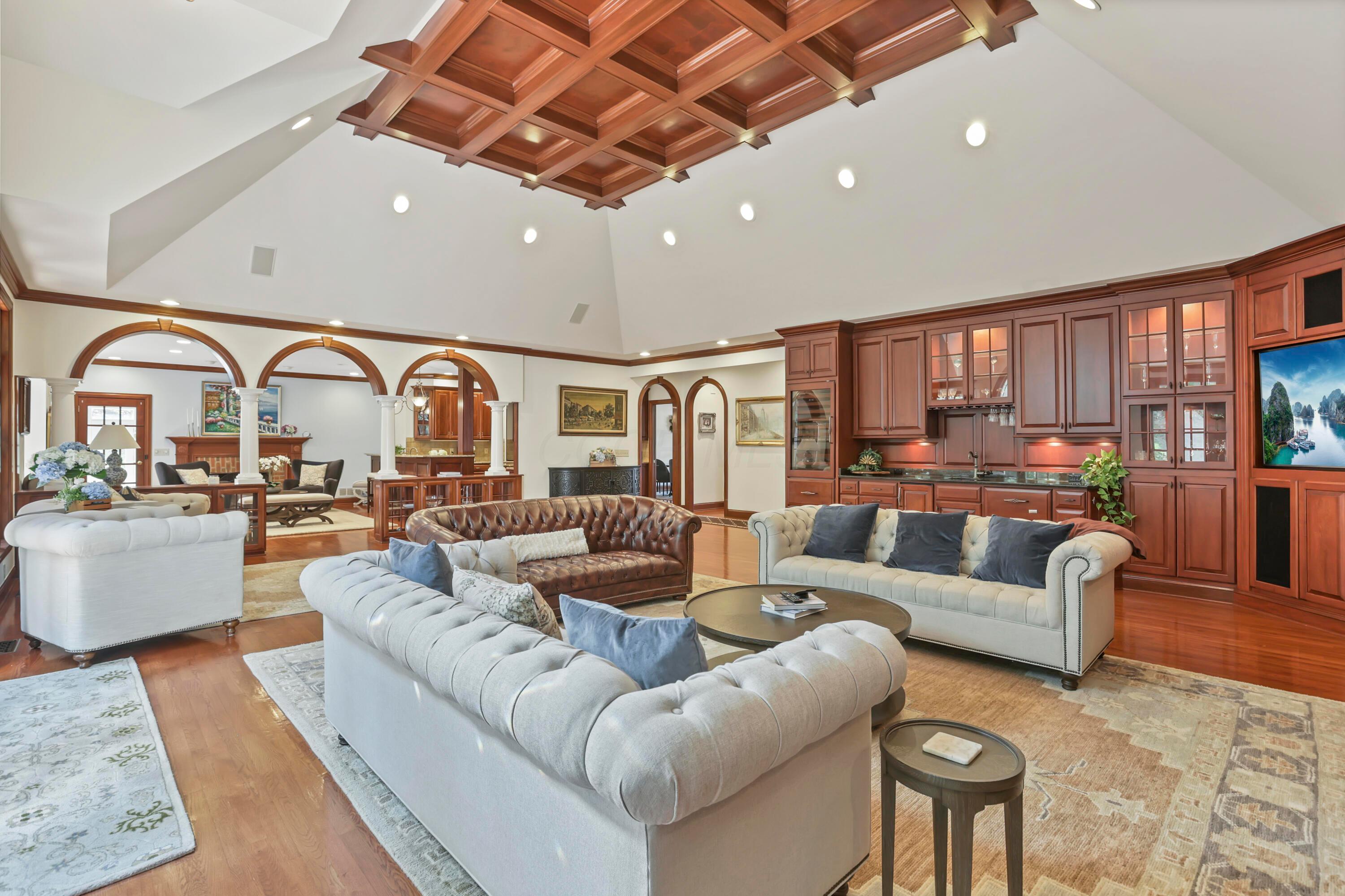 3575 State Rte 37 West Delaware, OH 43015 - Photo 31 of 106 Expansive living area featuring a coffered wood ceiling, vaulted white ceilings, recessed lighting, wood-finish flooring, and a built-in wet bar with wood cabinetry and a stone countertop