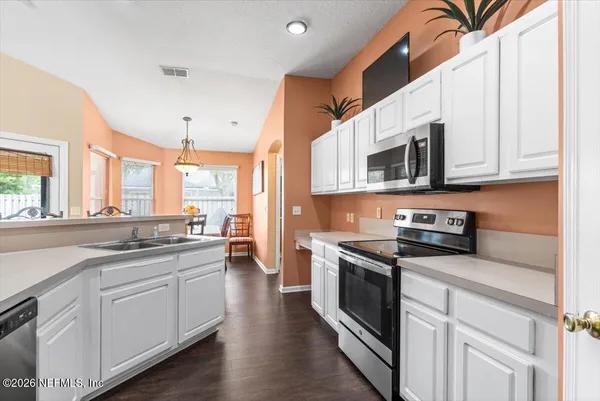 a kitchen with stainless steel appliances granite countertop a stove a sink and white cabinets