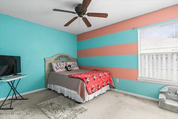 a bedroom with a bed a window and a flat screen tv
