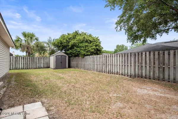 a view of a backyard with a trees and wooden fence