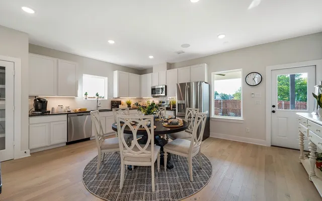 a kitchen with a dining table chairs and refrigerator