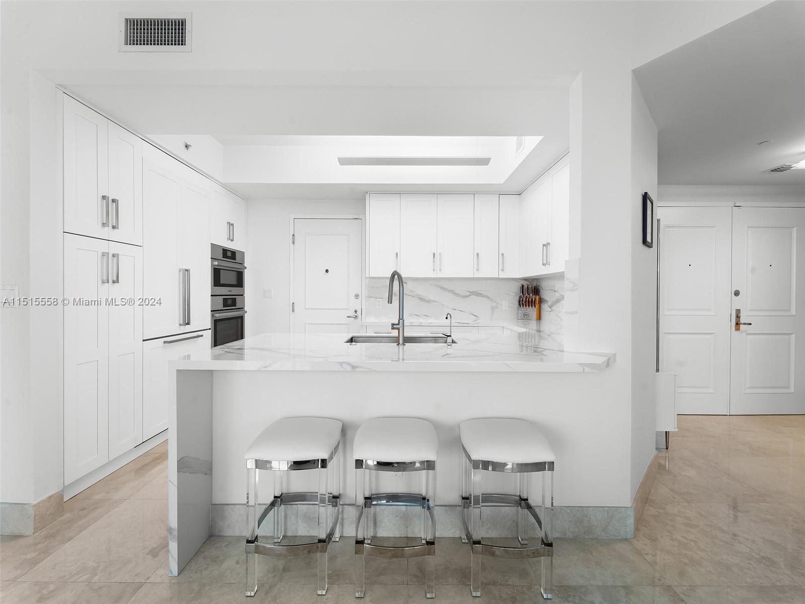 a kitchen with stainless steel appliances a chair and cabinets