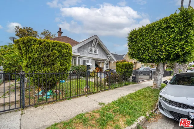 a front view of a house with a garden and a tree