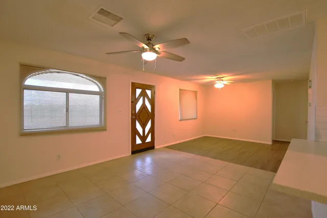 a view of an empty room with window and chandelier fan