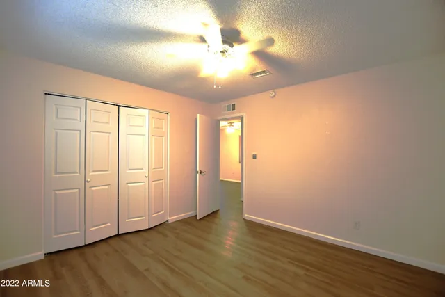 an empty room with wooden floor and fan