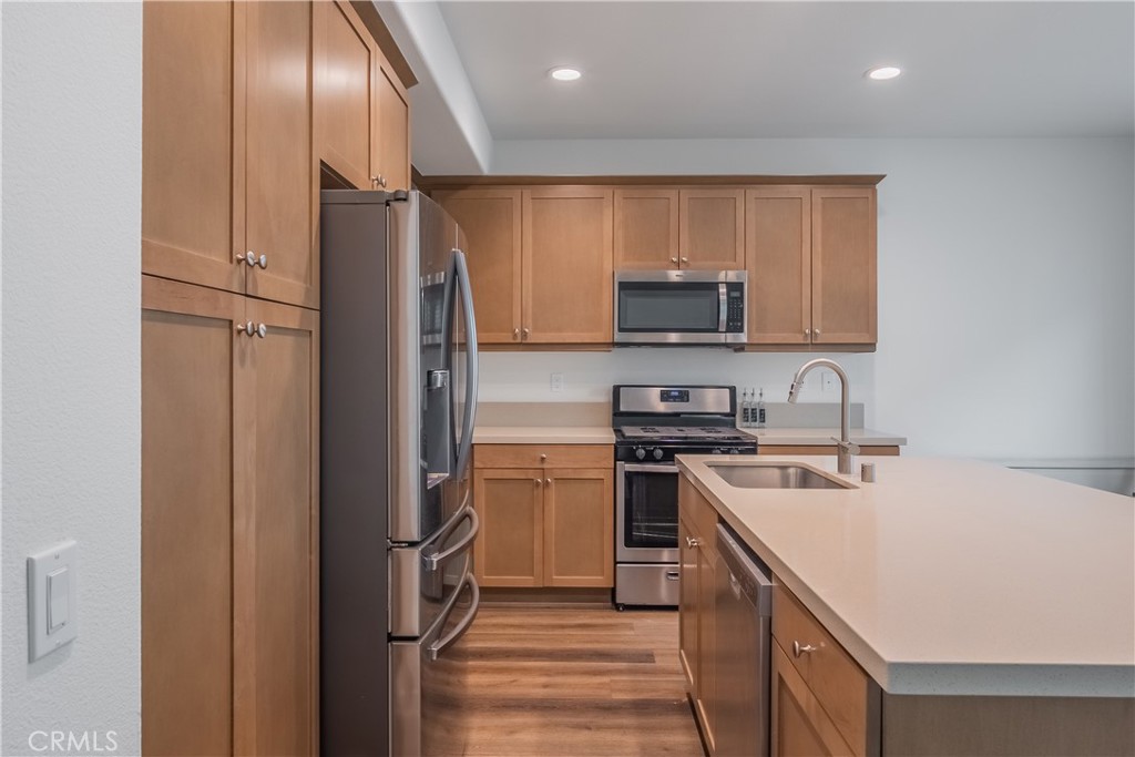 9513 Retreat Place Rancho Cucamonga, CA 91730 - Photo 10 of 49 a kitchen with a sink a refrigerator and a stove top oven with wooden floor