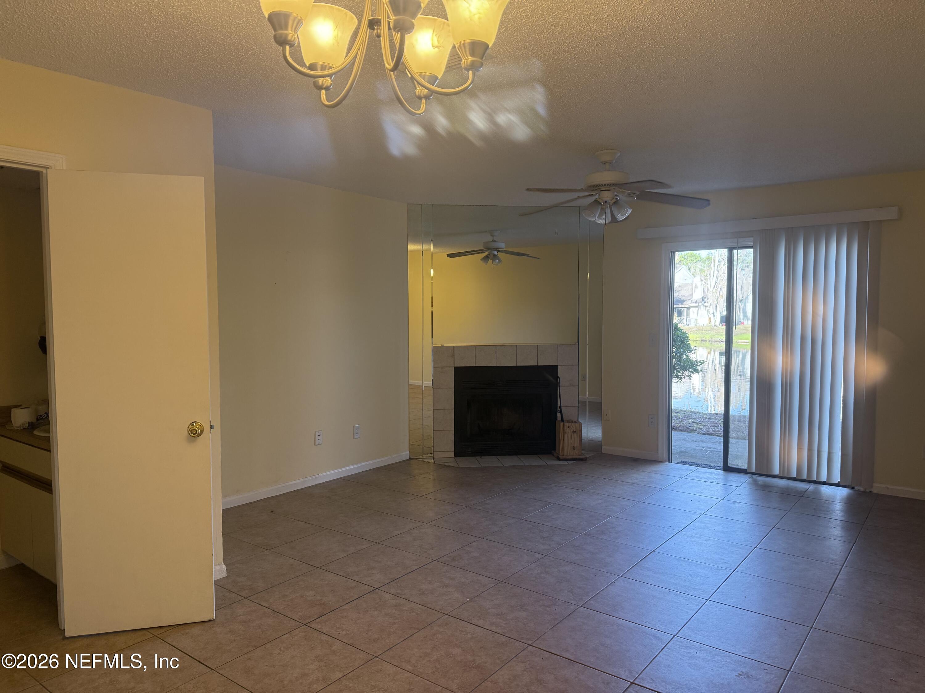 3801 Crown Point Road, Unit 2093 Jacksonville, FL 32257 - Photo 5 of 17 an empty room with a fireplace and chandelier fan
