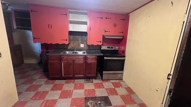 a kitchen with a sink a stove top oven a rug and a refrigerator