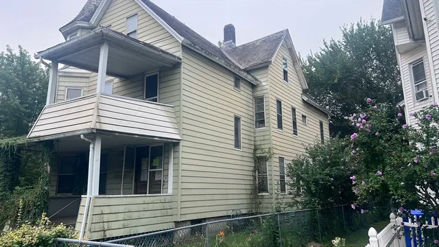 a view of a white house with large windows and flower plants