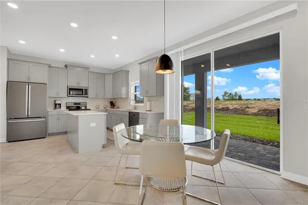 a kitchen with stainless steel appliances granite countertop a stove a sink a refrigerator and white cabinets with wooden floor