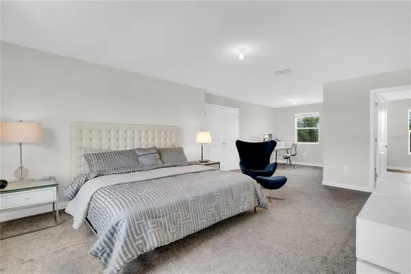 a spacious bedroom with a bed and lamp