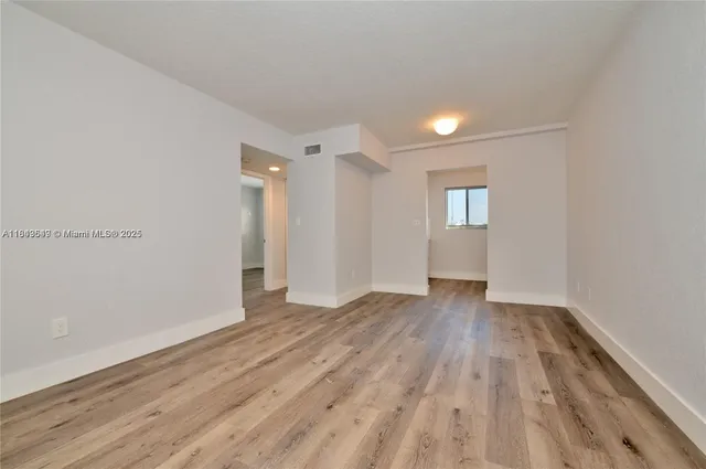 a view of an empty room with window and wooden floor