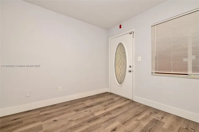 an empty room with wooden floor and window