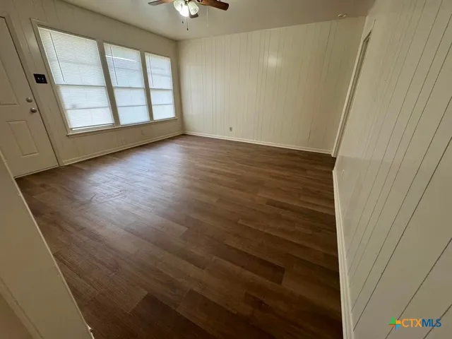 a view of an empty room with wooden floor and a window