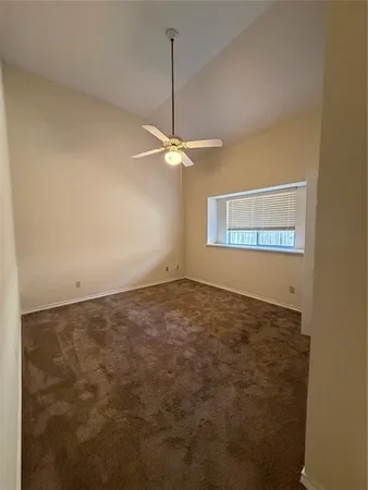 an empty room with a ceiling fan and a window