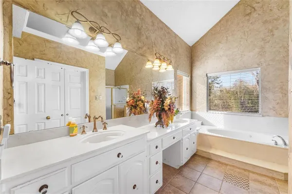 a spacious bathroom with a double vanity sink a mirror a bathtub and next to a window