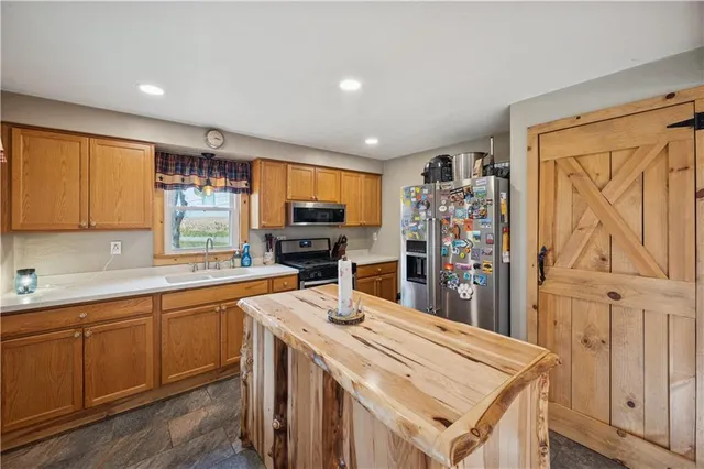 a kitchen with stainless steel appliances a sink a stove a refrigerator cabinets and a window