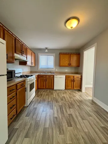 a kitchen with stainless steel appliances granite countertop a stove top oven a sink dishwasher and a microwave with wooden floor