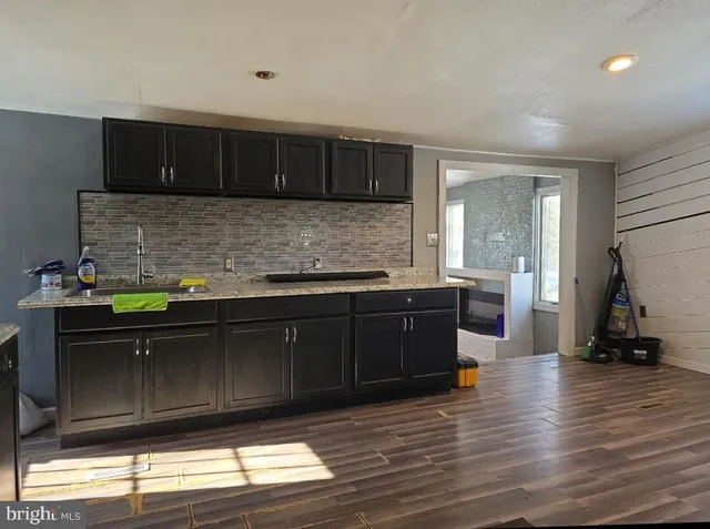 a kitchen with granite countertop wooden cabinets and wooden floor