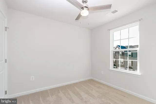 an empty room with a window and ceiling fan