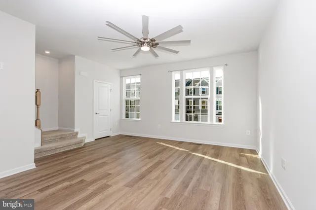 an empty room with wooden floor fan and windows