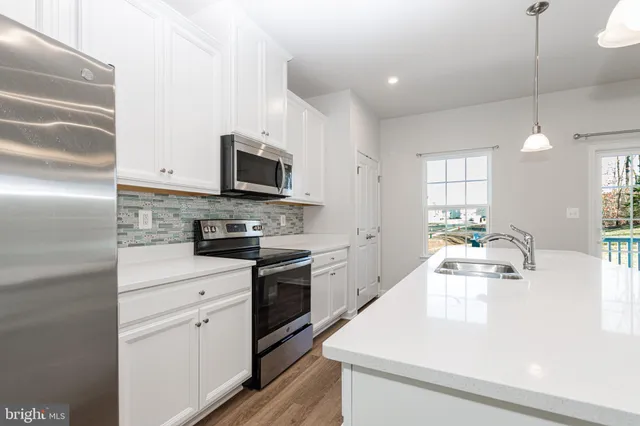 a kitchen with kitchen island white cabinets appliances and a sink