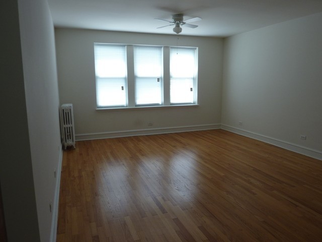 5058 North Claremont Avenue, Unit 2E Chicago, IL 60625 - Photo 5 of 12 an empty room with wooden floor and windows