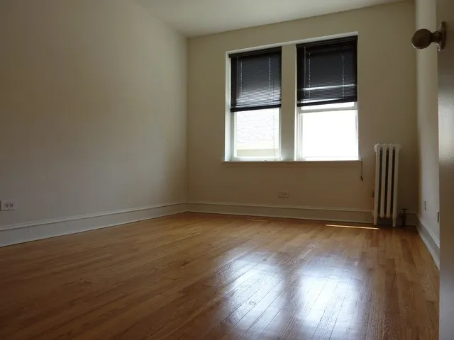 an empty room with wooden floor & closet area