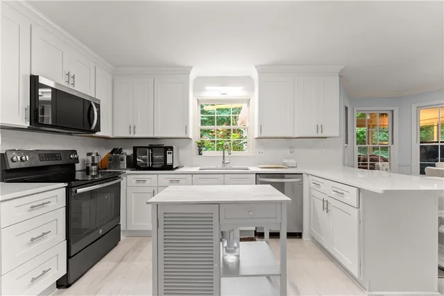 a kitchen with a sink white cabinets and wooden floor