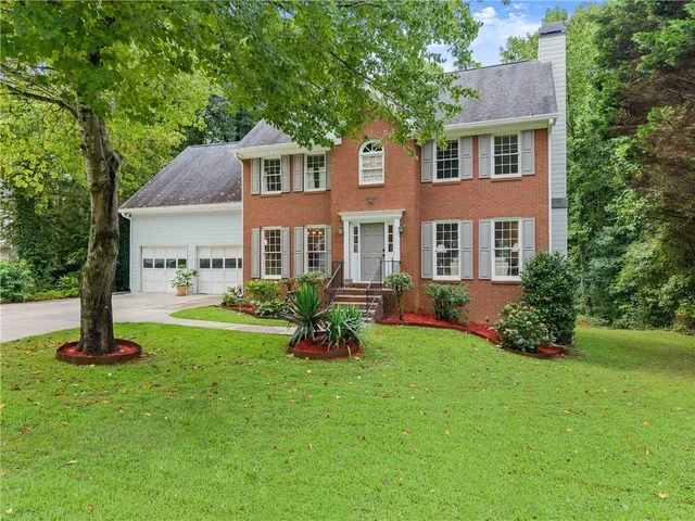 a front view of a house with garden and trees