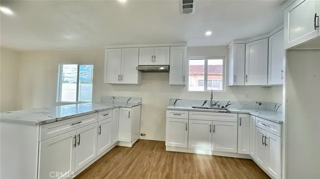 a kitchen with white cabinets sink and stove