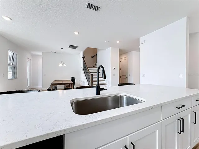 a kitchen with stainless steel appliances a stove a sink a refrigerator white cabinets and chairs