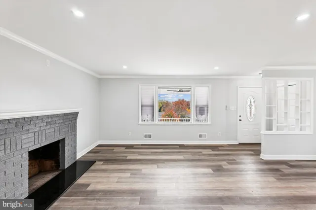 a view of an empty room with wooden floor and a fireplace