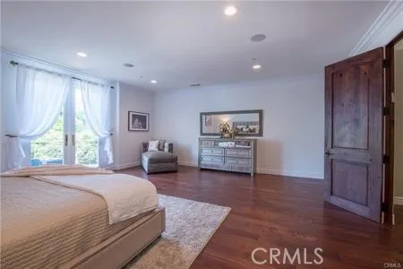 a spacious bedroom with a bed and wooden floor