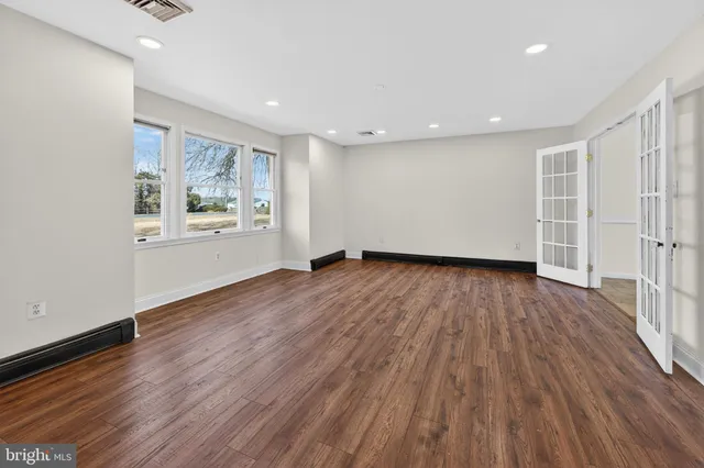 an empty room with wooden floor and windows