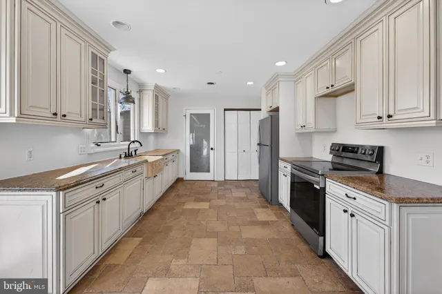 a large kitchen with stainless steel appliances granite countertop a stove a sink and white cabinets