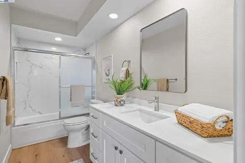 a bathroom with a granite countertop sink a toilet and shower