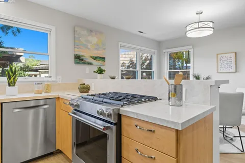 a kitchen with stainless steel appliances granite countertop a stove a sink dishwasher and a refrigerator with wooden floor