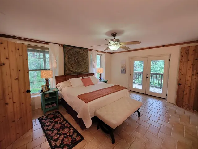 a bedroom with a bed a rug dresser and a chandelier