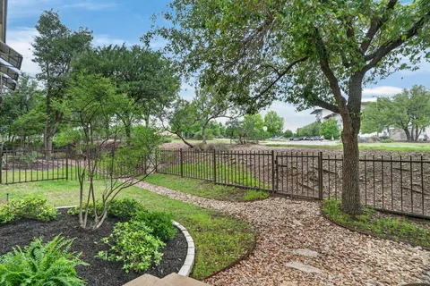 a view of a backyard with a fence and a tree