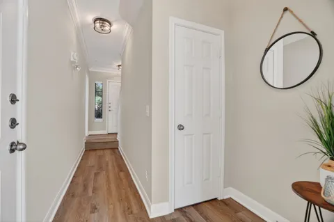 a view of a hallway with wooden floor and a bathroom
