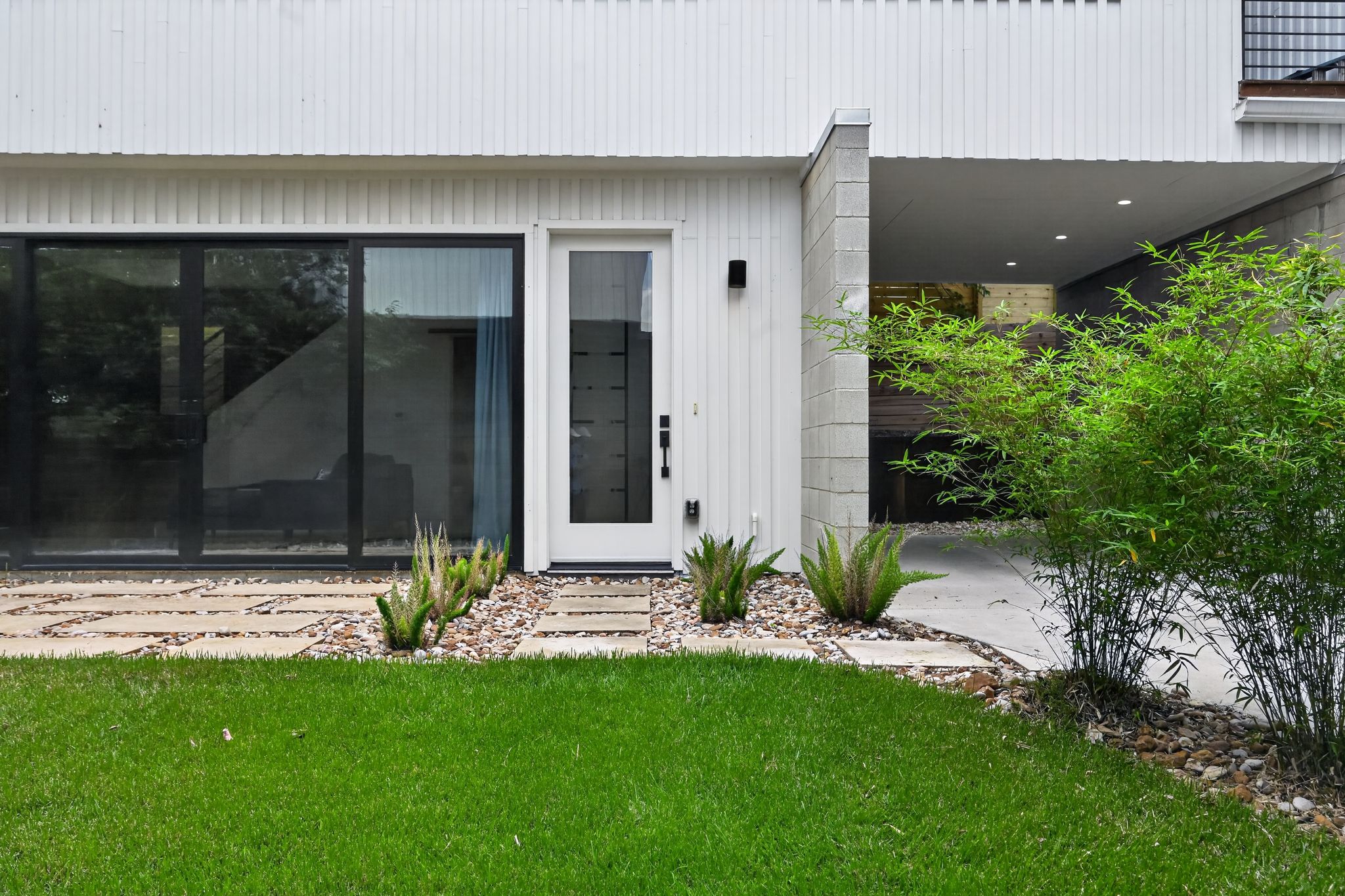 1206 Luna Street, Unit 2 Austin, TX 78721 - Photo 7 of 30 The property features a white exterior, large windows, and a front entry door with a frosted glass panel
