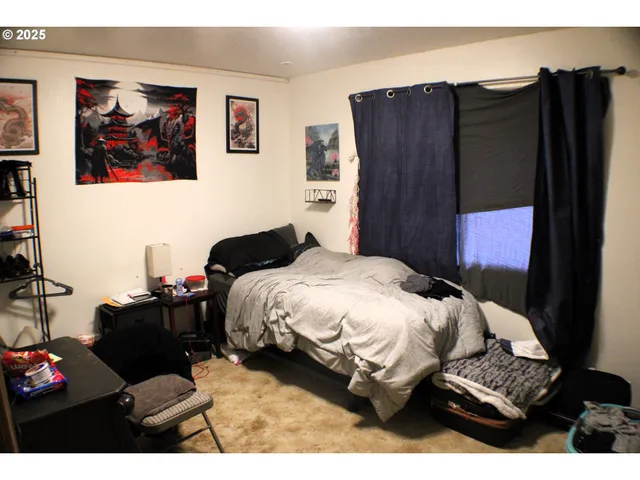 a bedroom with bed and a painting on the wall