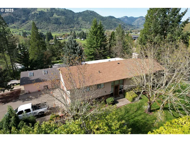 an aerial view of residential house with outdoor space and trees all around